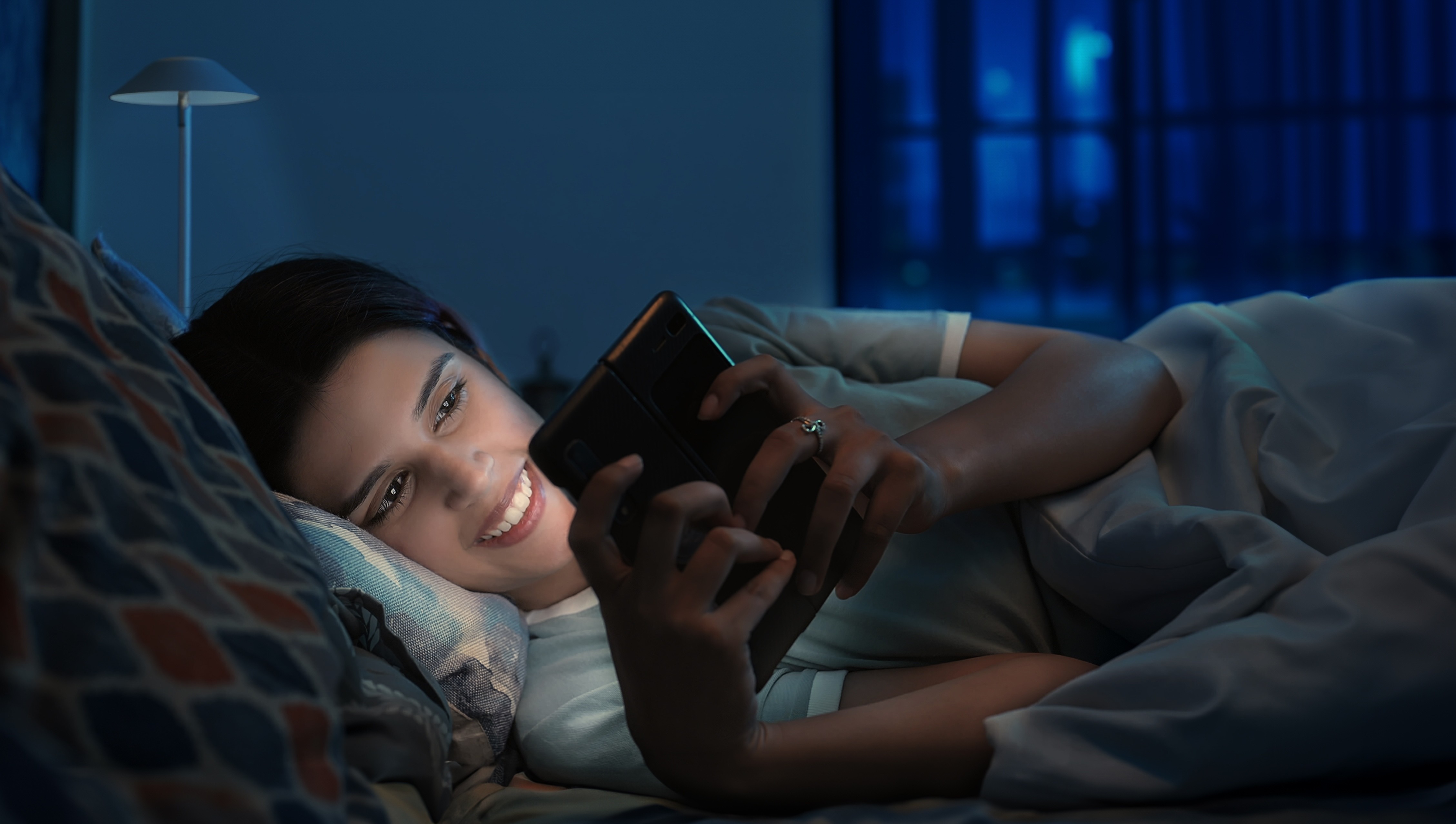 Attractive young Indian woman reading in bed.