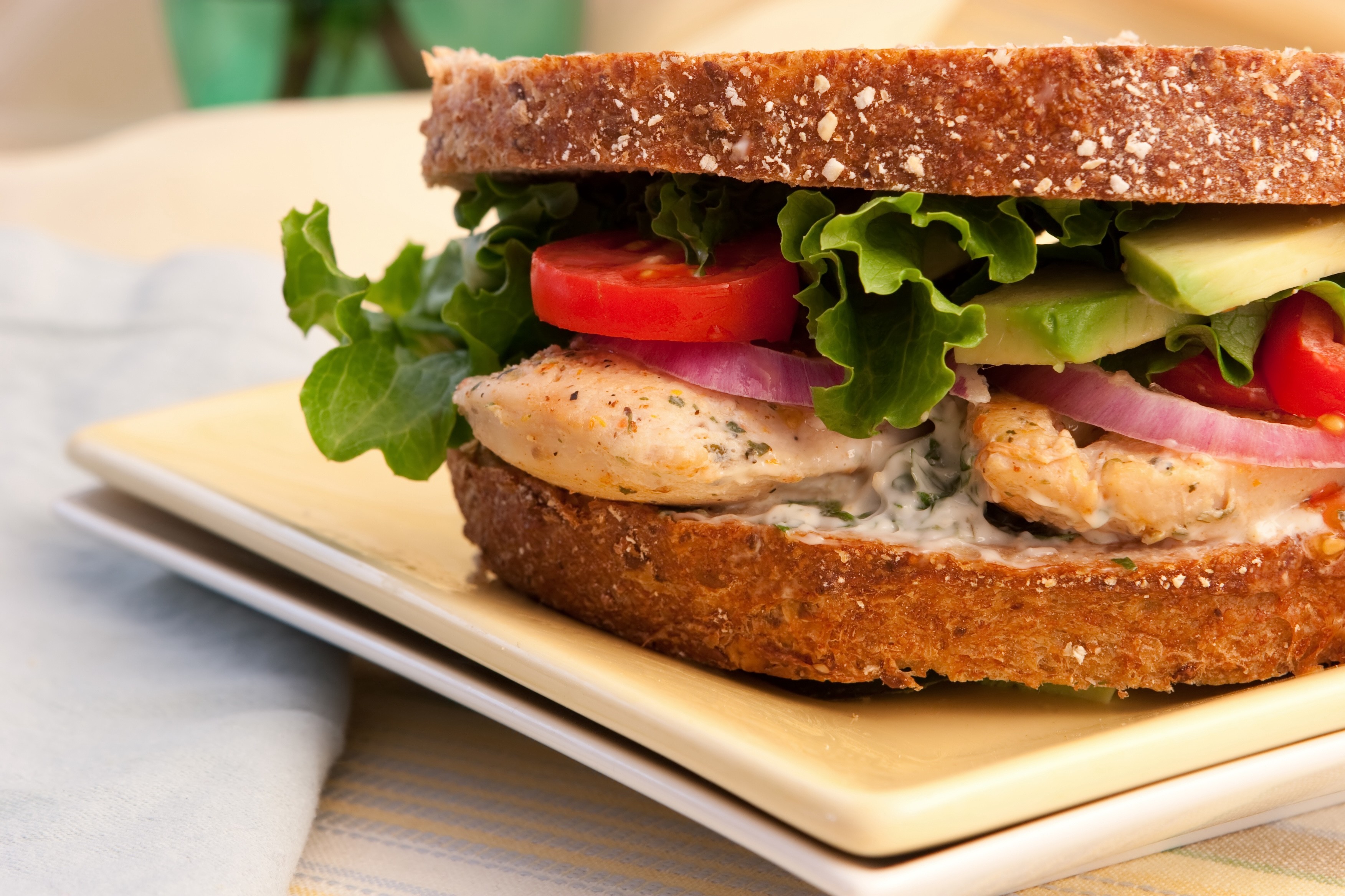 Grilled chicken  with avocado, tomato, greens and onion on whole wheat bread .