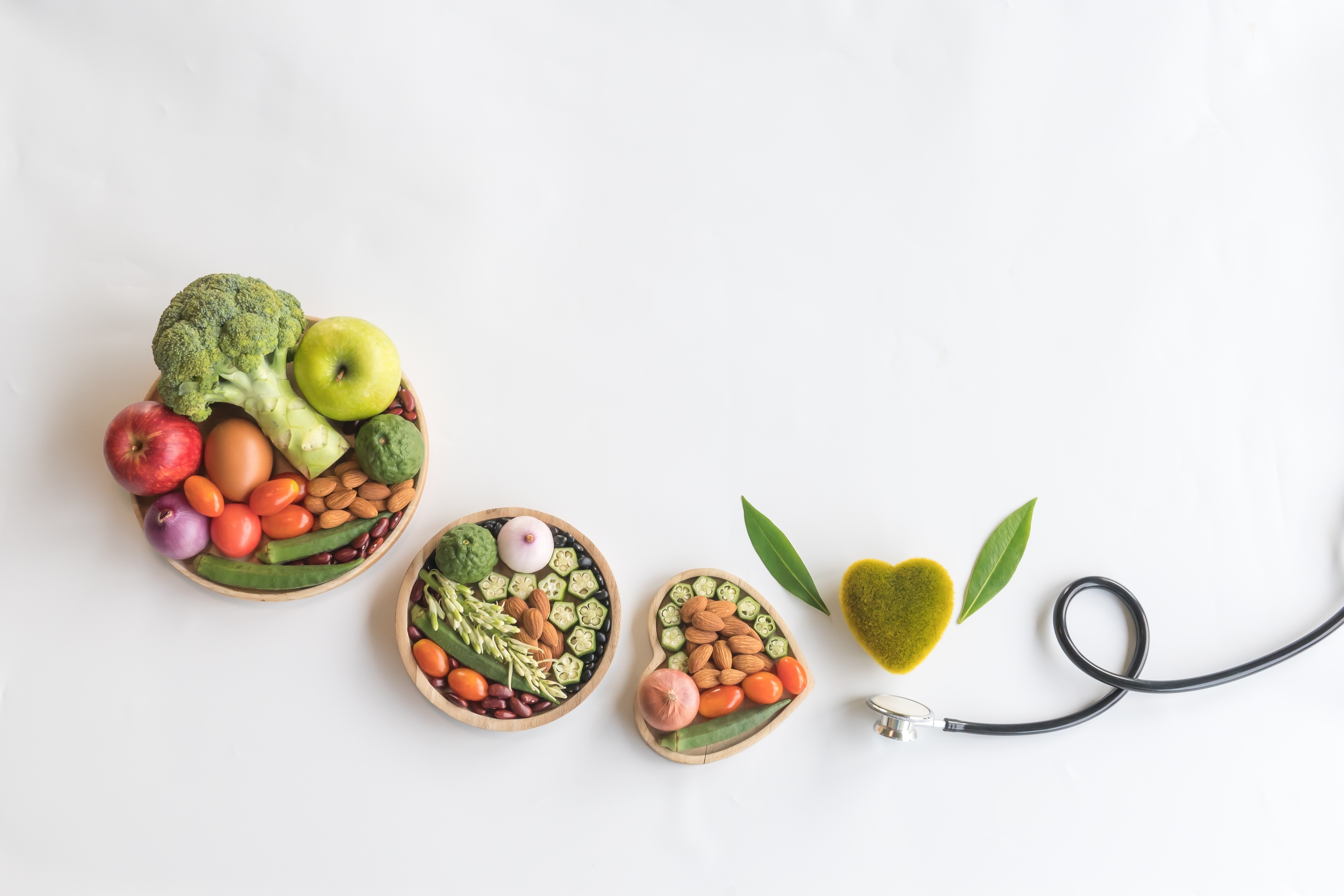 Different whole foods, in wooden bowls with a stethoscope promoting wellness