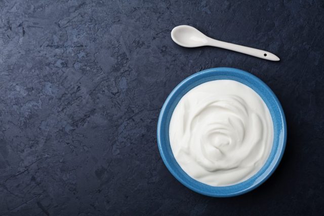 Greek,Yogurt,In,Blue,Bowl,On,Black,Table,Top,View.