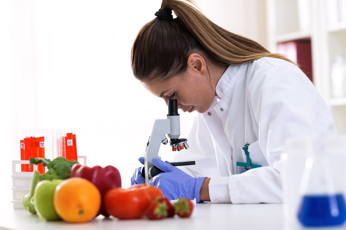 A scientist looking at food under a microscope.