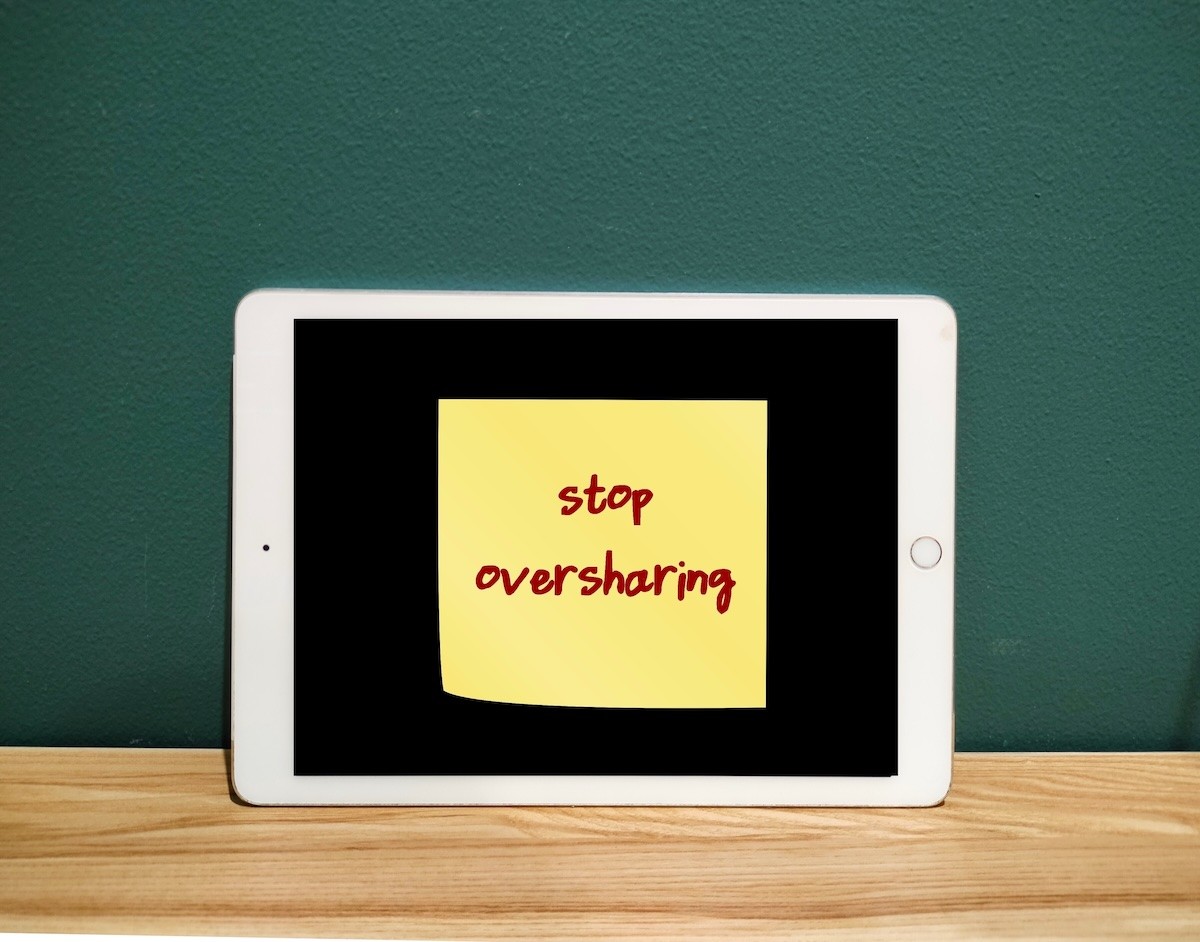 A sticky note with the words 'Stop Oversharing' stuck on a tablet.