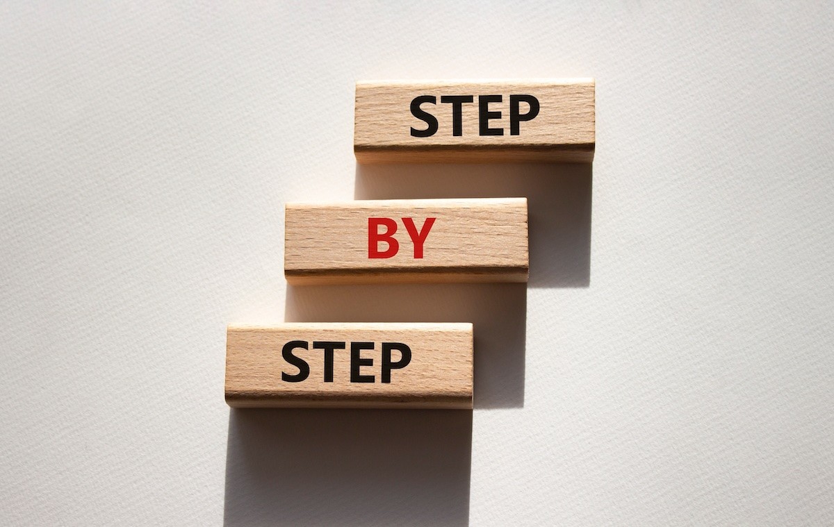 Wooden blocks with the words "step by step" on them.