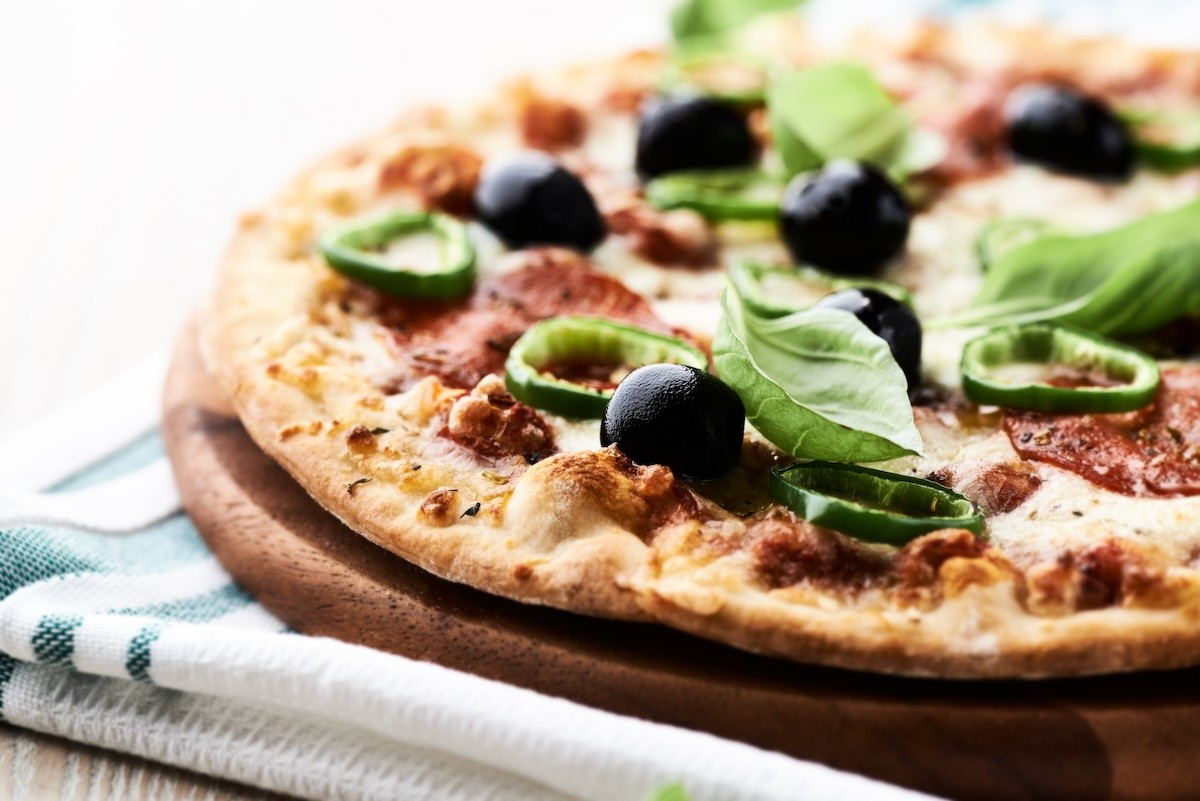 Pizza with salami, black olives, jalapeños and basil.