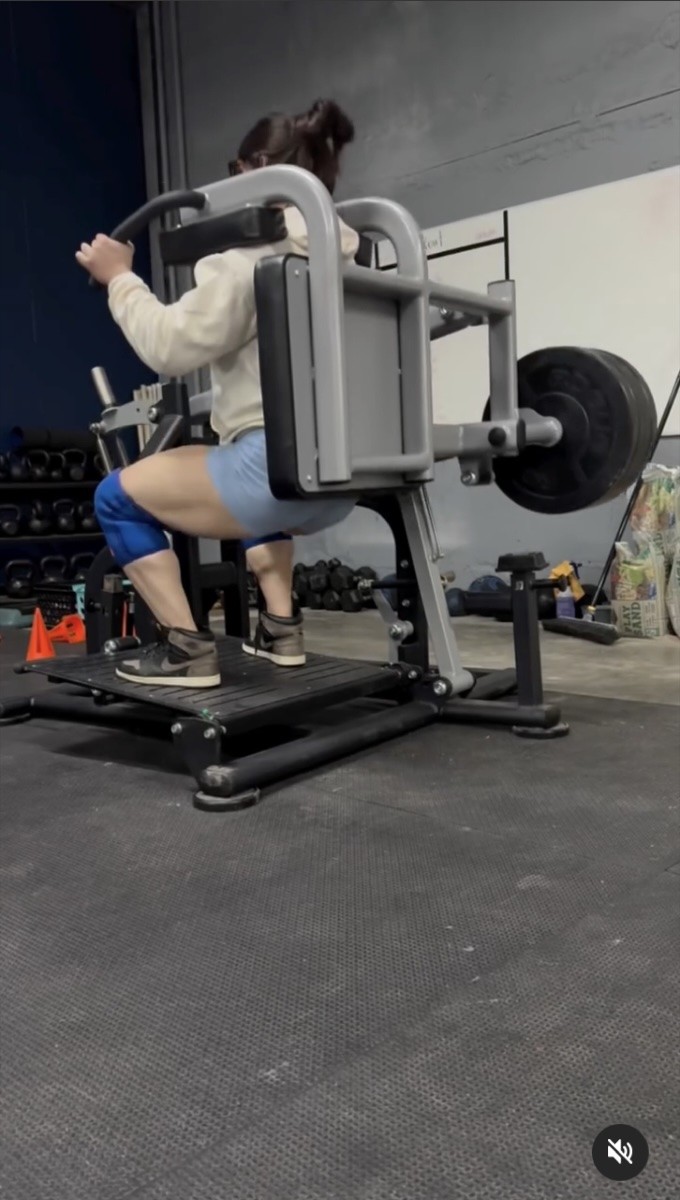 Julia Danielle Whitesel is seen doing squats with a vertical squat up machine.