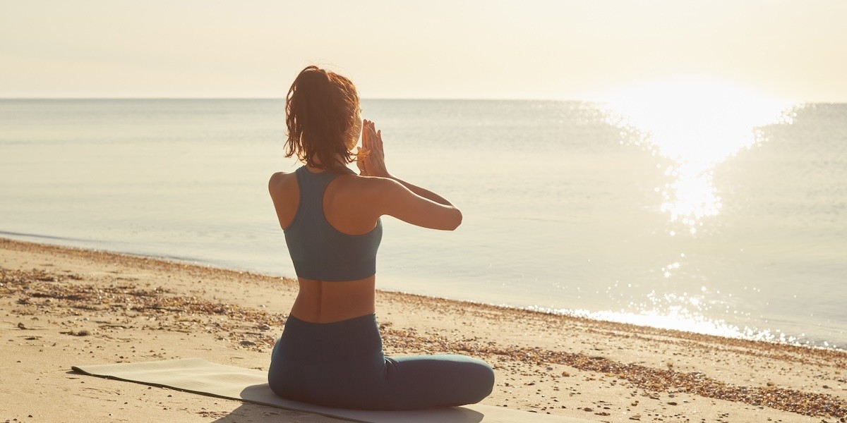 A woman does morning yoga on the beach.