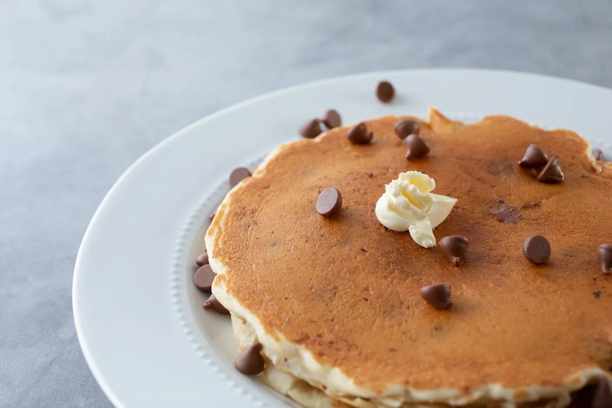 Chocolate chip pancakes on a white plate with a light background.