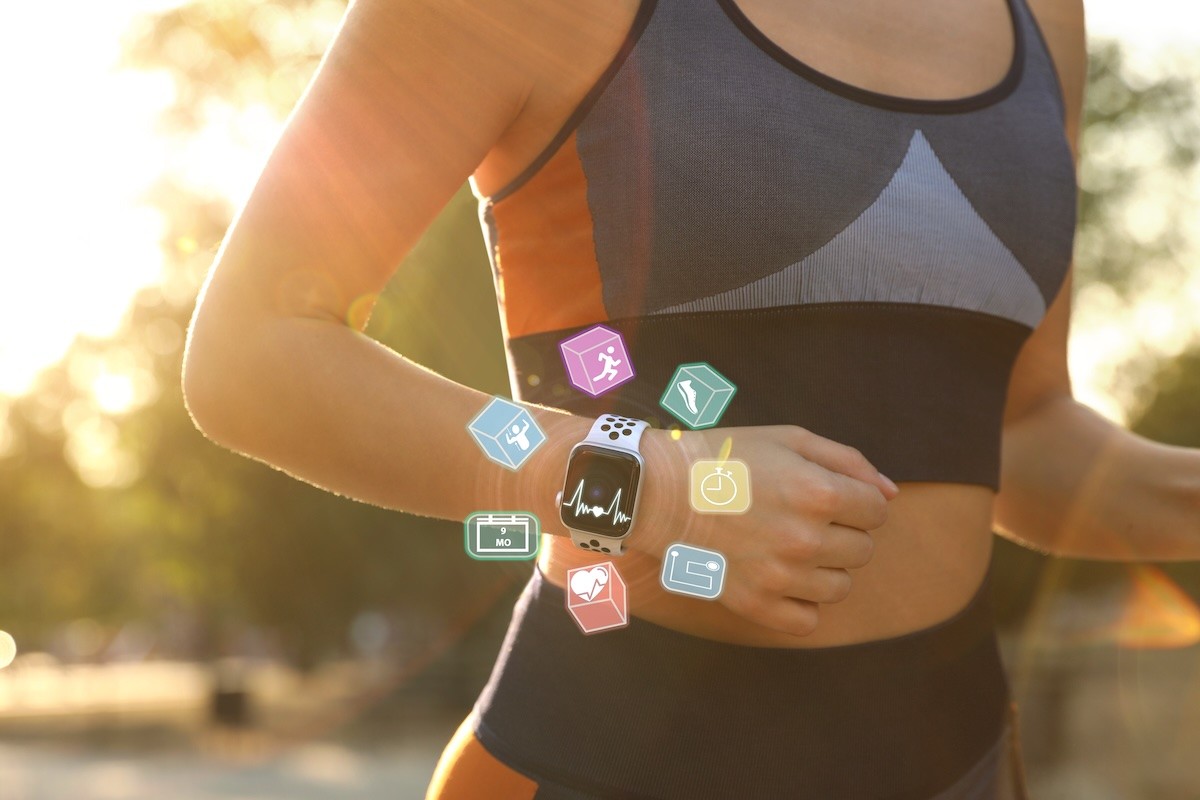 Fit woman wearing a smart watch to track her heart rate while jogging.