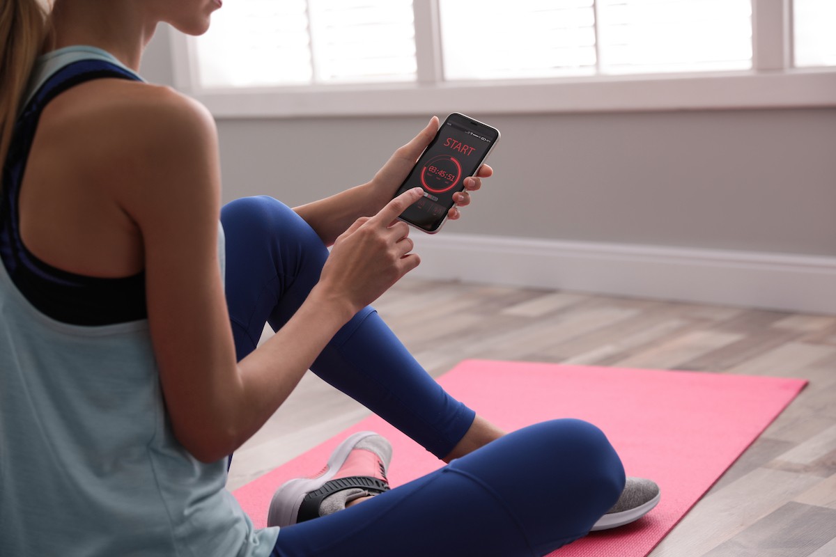 Young,Woman,Using,Fitness,App,On,Smartphone,Indoors,,Closeup