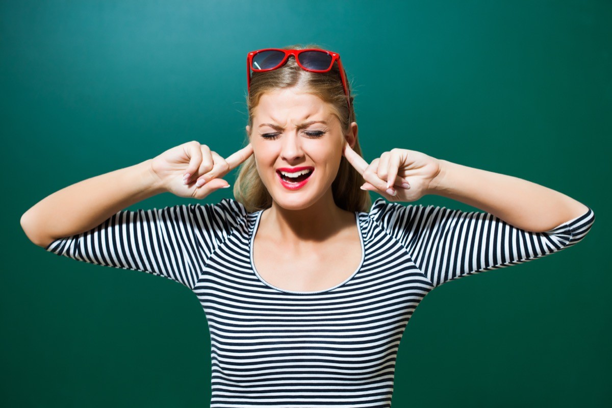 Blonde woman plugging her ears.