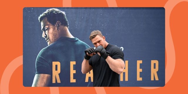 Alan Ritchson boxing in front of Reacher poster